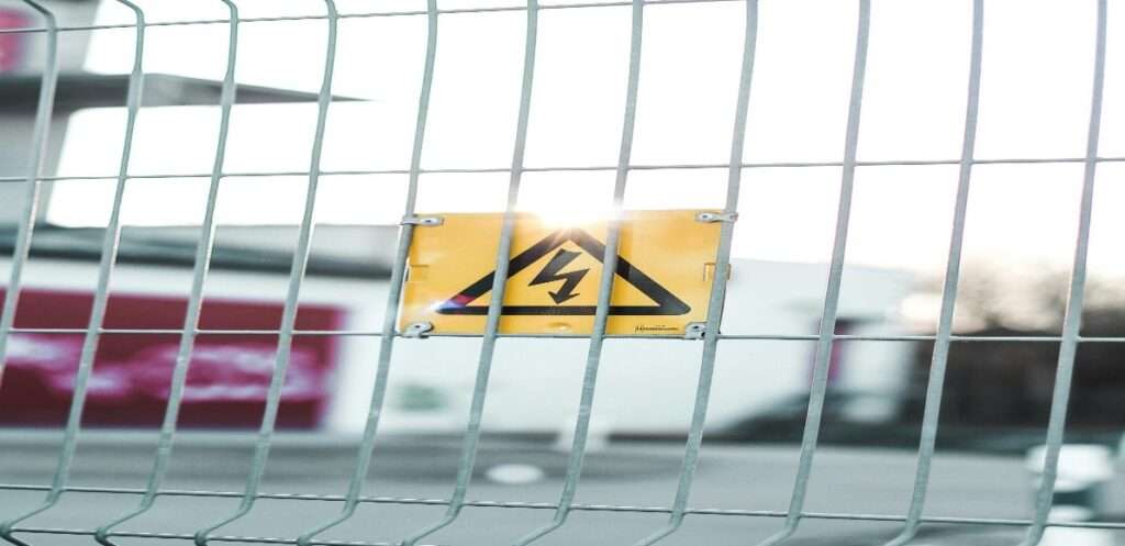 An image of a fence with a sign displaying important electrical safety rules and signage. Take heed!